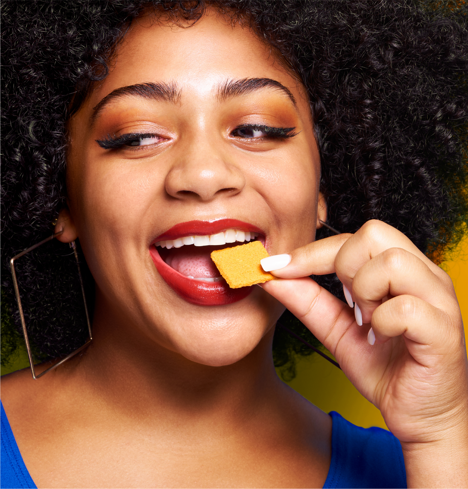 Smiling woman eating cheese cracker